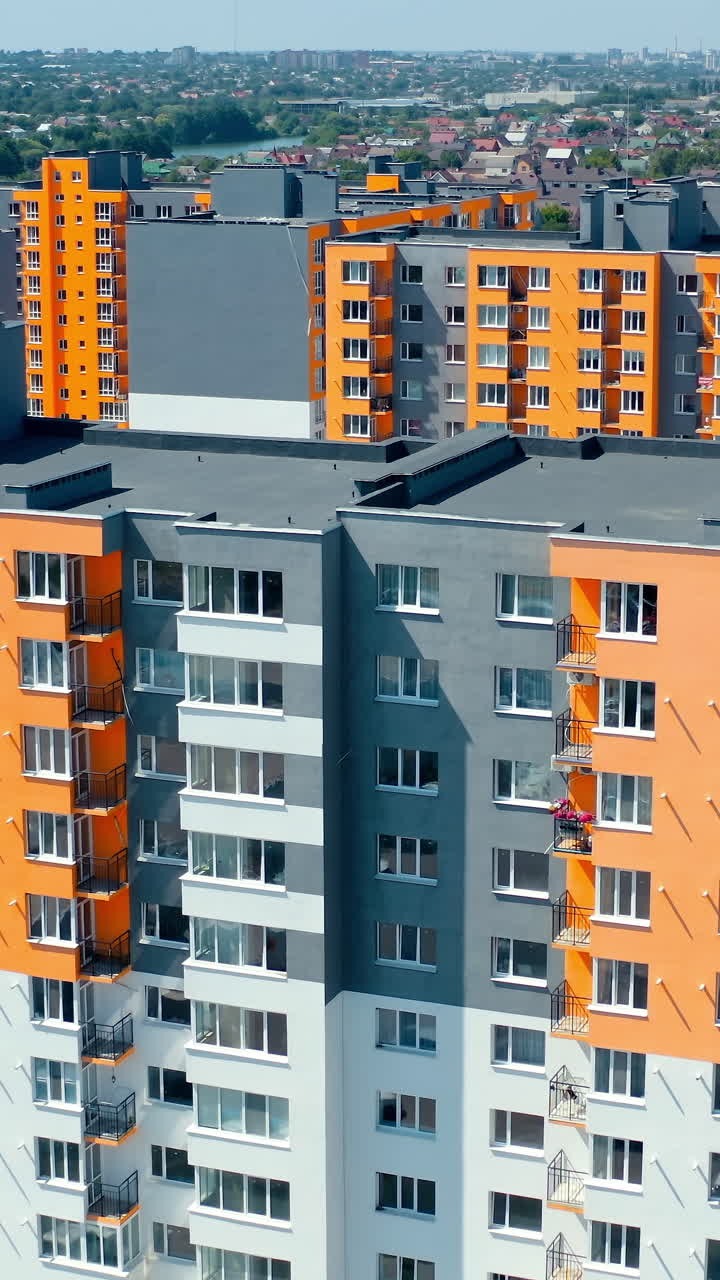 Facade of a modern apartment building. Colorful walls of a new multi-storey building with balconies and windows. High residential building in sunny day. Vertical video
