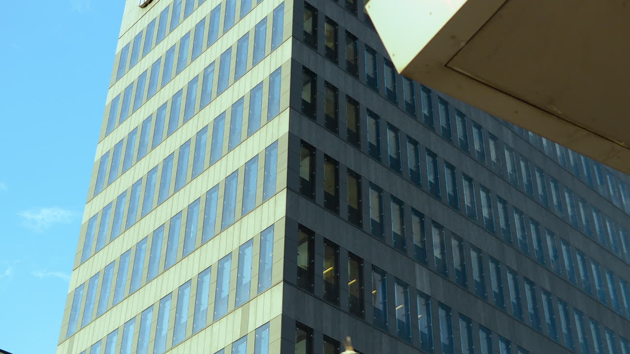 A modern office building with glass windows against a clear blue sky