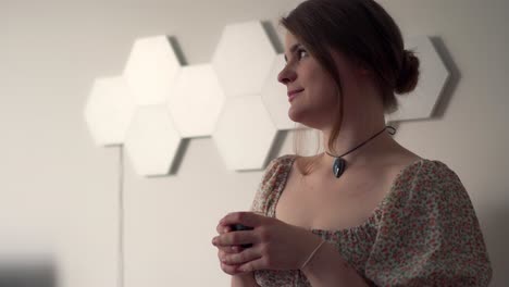 hermosa mujer joven con maquillaje conservador disfrutando de café en casa