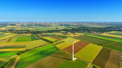wind farm spans green land. wind turbines rotate against a clear blue sky over expansive green and brown fields during daylight