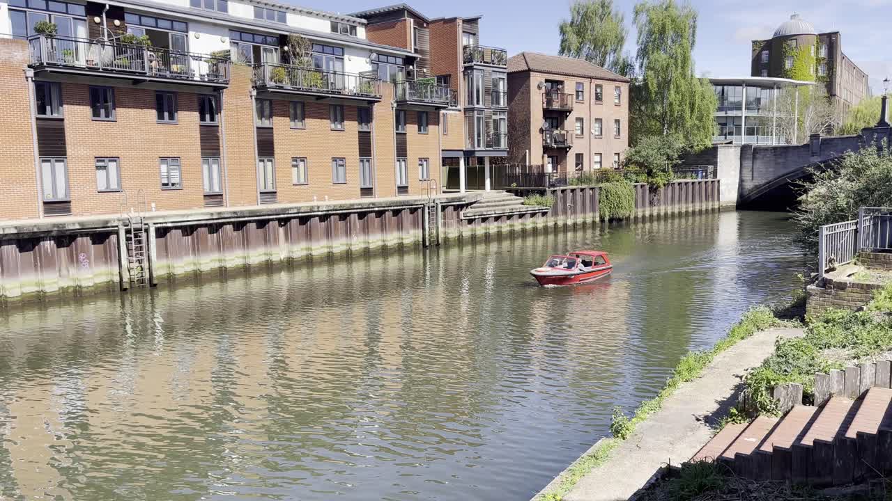 Boat on River Wensum with modern riverside buildings in Norwich