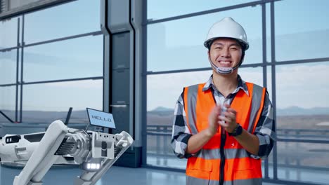 ingeniero aplaudiendo frente al robot en una instalación industrial moderna