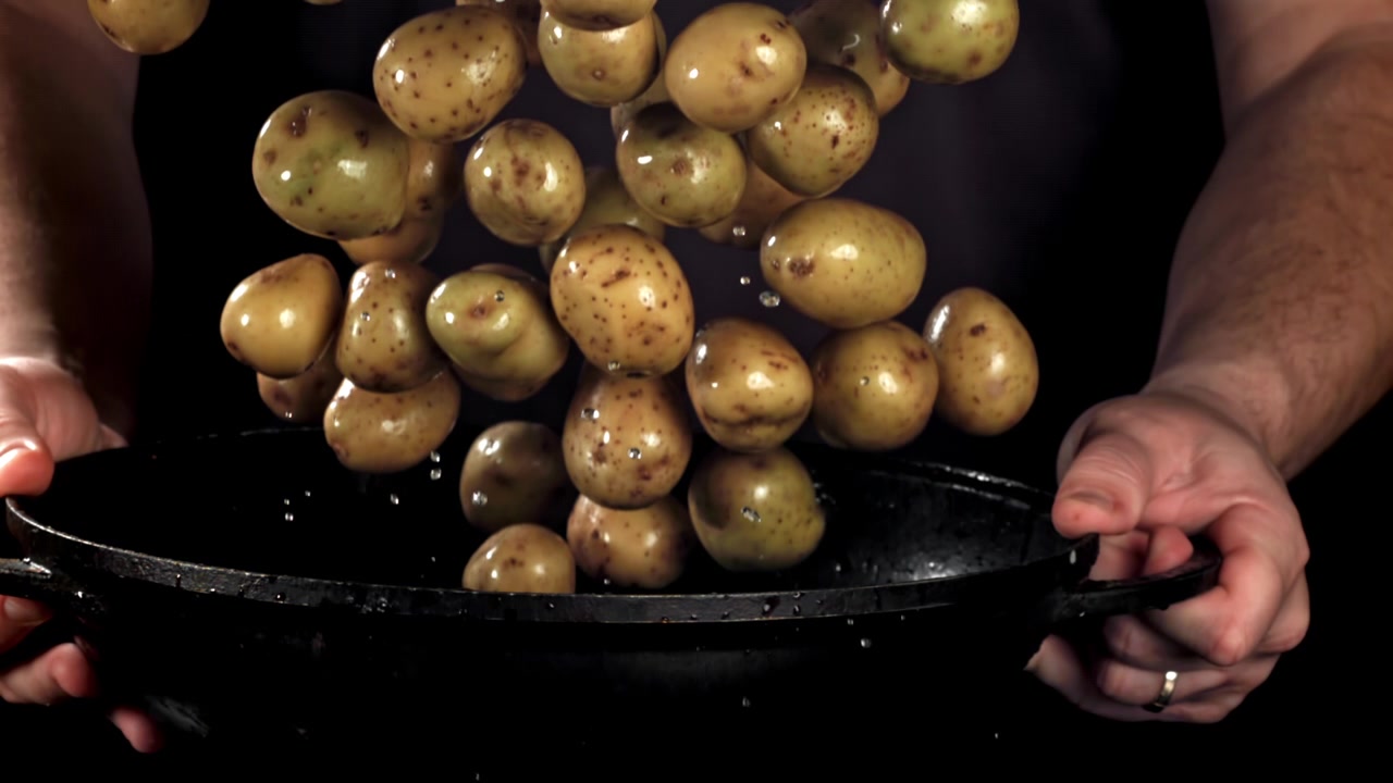 Caduta di patate novelle fresche in una padella di ghisa nera