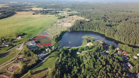descripción aérea del lago al lado del estadio con bosque en segundo plano
