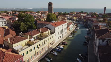 boats moored near building in canal of venice, aerial ascend view