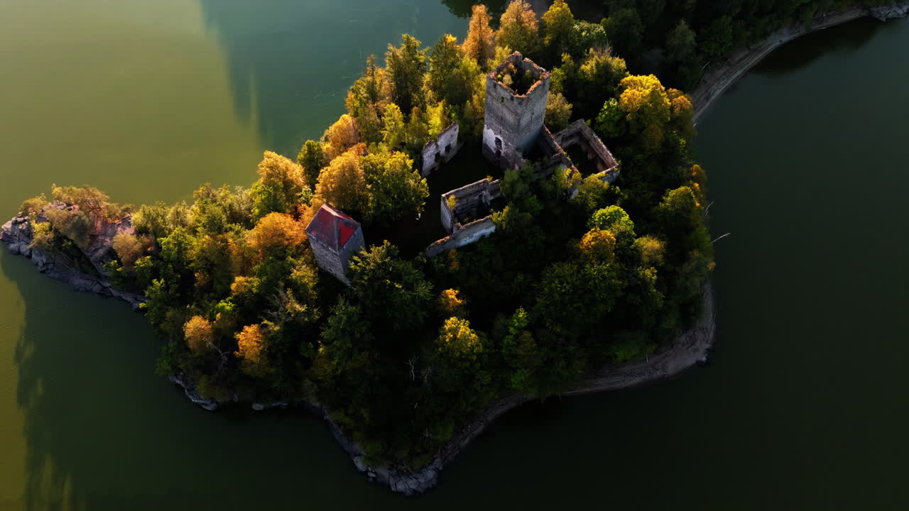 Panoramica aerea dell'incredibile Castello di Ottenstein nel mezzo del bacino artificiale, un bagliore dorato illumina gli alberi gialli autunnali