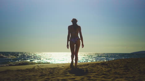 woman walking on the beach at sunset