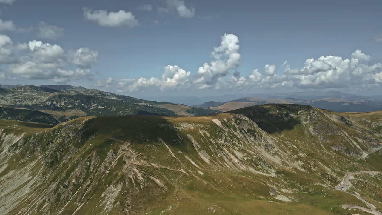 Vista maestosa delle montagne della Transalpina in Romania, che mostra terreni accidentati, strade tortuose e nuvole drammatiche