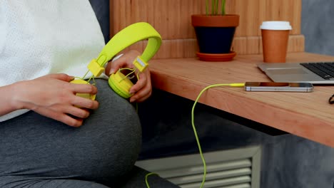 mujer embarazada colocando auriculares en su vientre 4k