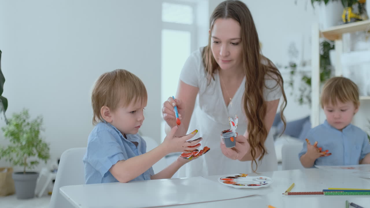 двое детей мальчиков и мать занимаются творческим развитием, делая домашнее задание, пальцами на бумаге. развитие тактильных ощущений и небольшой математики.