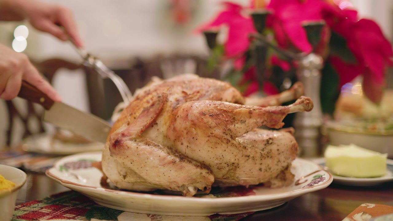 Affettare il tacchino arrosto a una tavola festiva per la cena delle vacanze.