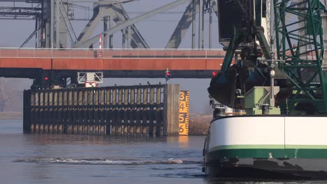 primer plano de un barco de dragado frente a un corredor de puente levadizo que limpia la vía fluvial del río ijssel para buques de carga en zutphen, países bajos
