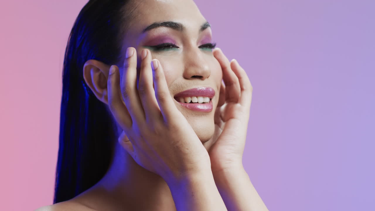 Donna sorridente di etnia mista con capelli neri e trucco che si tocca il viso, spazio per il testo, al rallentatore