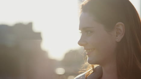 primer plano de una mujer blanca millennial de pie al aire libre sonriendo, tiro en la cabeza