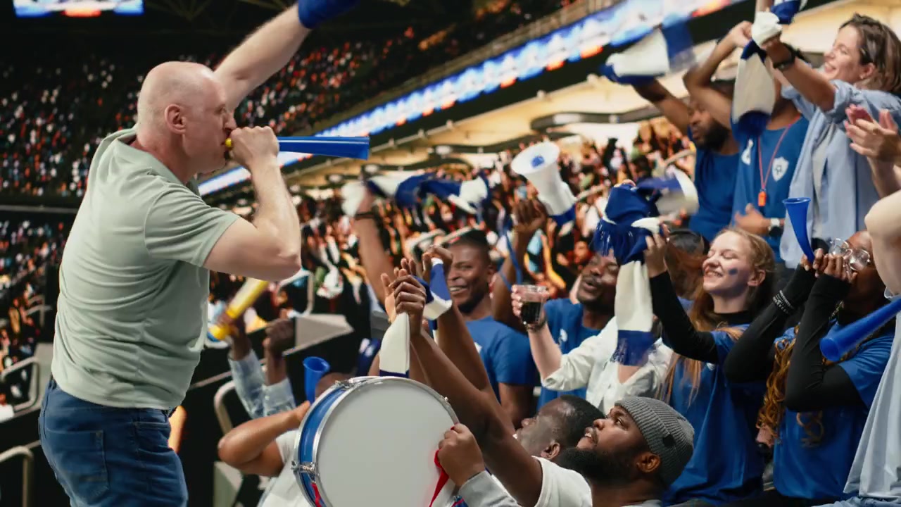 Energético aficionado al fútbol soplando una vuvuzela azul en la grada del estadio