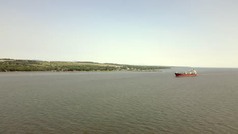 Wenn-Sie-über-Den-Fluss-Gleiten,-Werden-Sie-Von-Einem-Prachtvollen-Roten-Frachtschiff-Angezogen,-Das-Anmutig-Dahinfährt-–-Ein-Beweis-Für-Das-Lebhafte-Maritime-Treiben-In-Der-Region