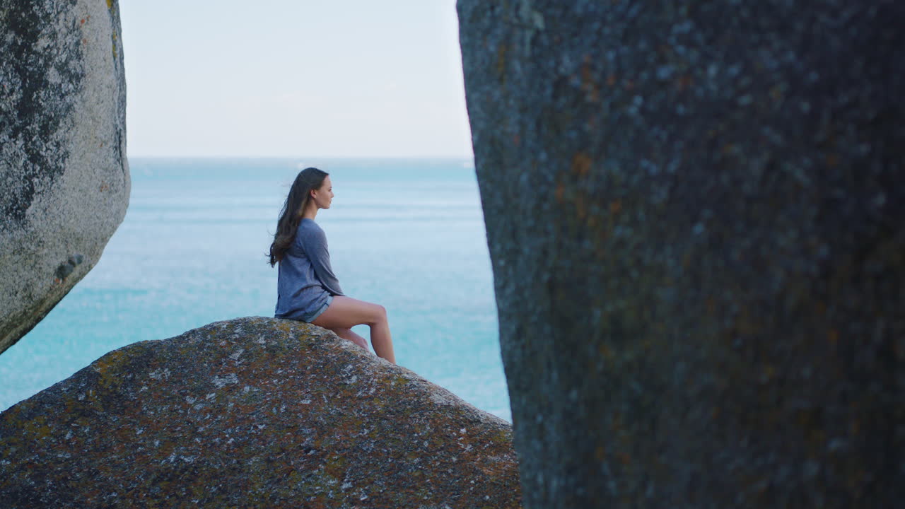 바다 의 바위 위에 앉아 있는 여자