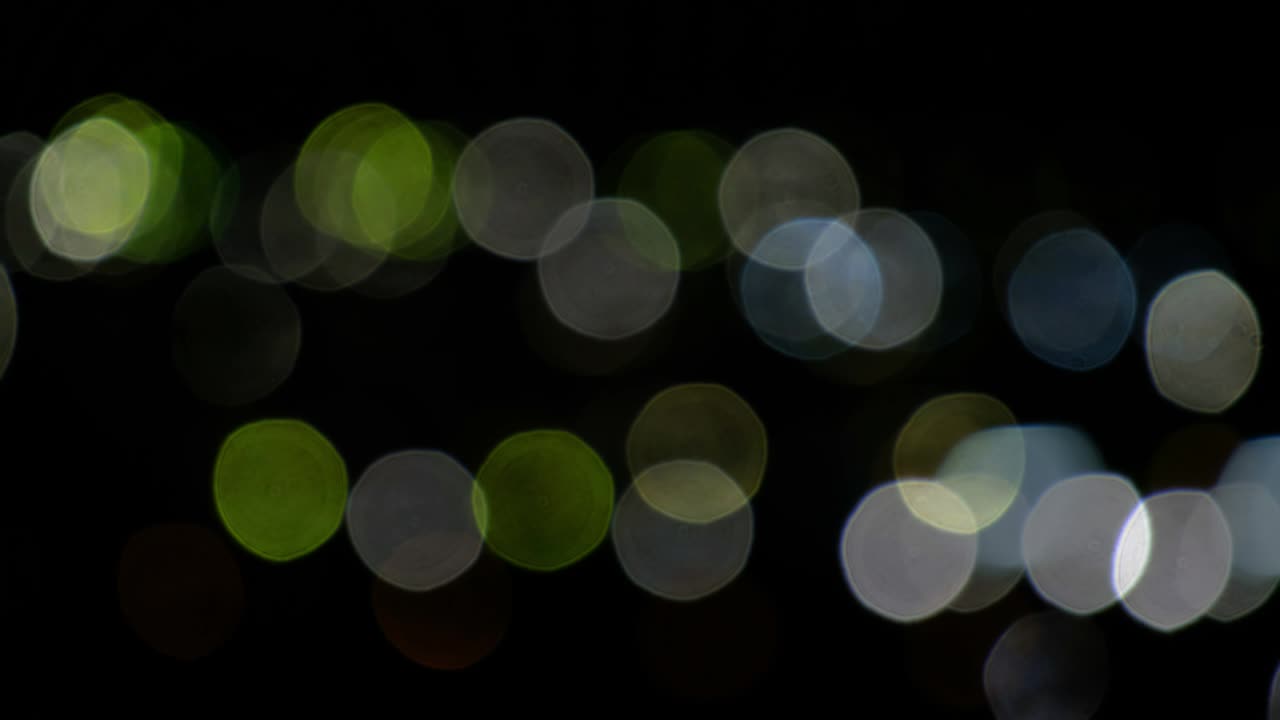 Bokeh-Video-Hintergrund aus Lichtkreisen auf Schwarz. Linsen-Lichtlecks-Effekt.