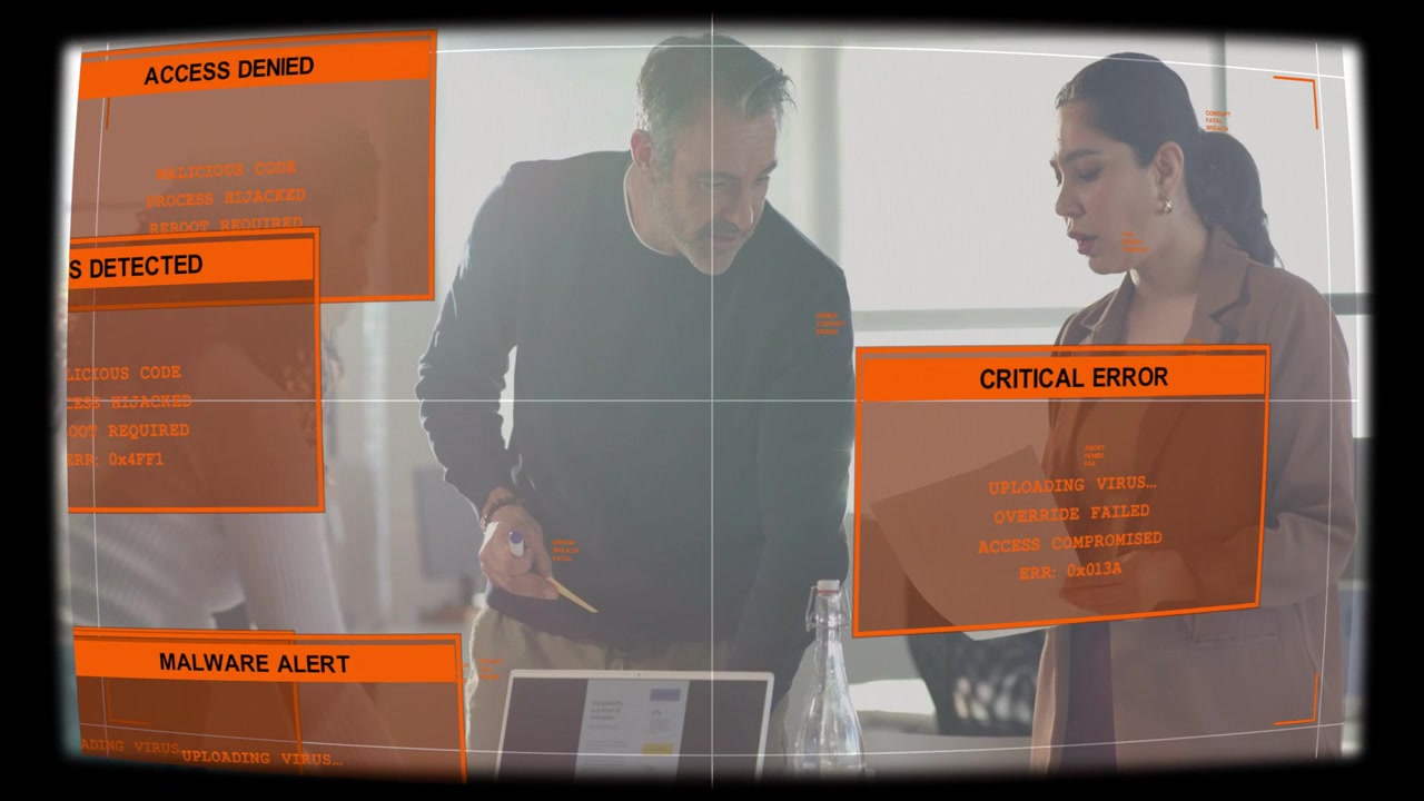 Orange alerts appearing, colleagues leaning over laptop, writing notes and pointing to stop virus
