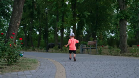 rear view of a toddler running by the alley. active energetic kid in the park in summer.