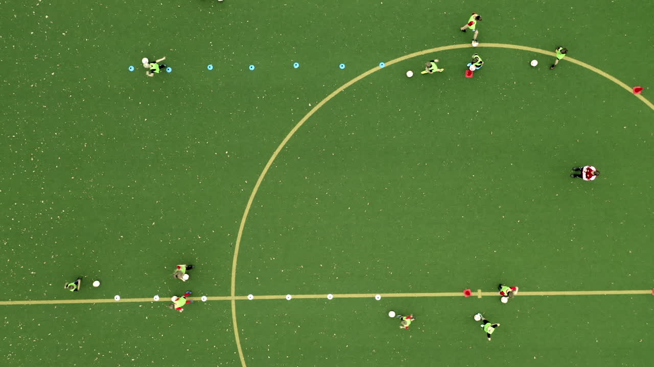 녹색 축구장 아이들은 코치 4k 드론 탑다운, 버드 뷰와 함께 훈련 세션에서 축구를 합니다.