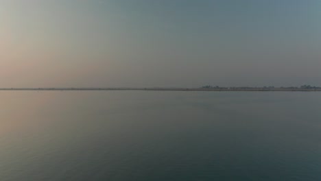 Dawn-at-Inle-Lake-with-narrowboat-floating-on-water,-aerial