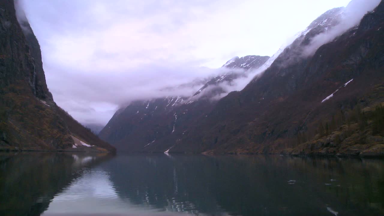 skyer og tåge hænger over en fjord i norge i timelapse