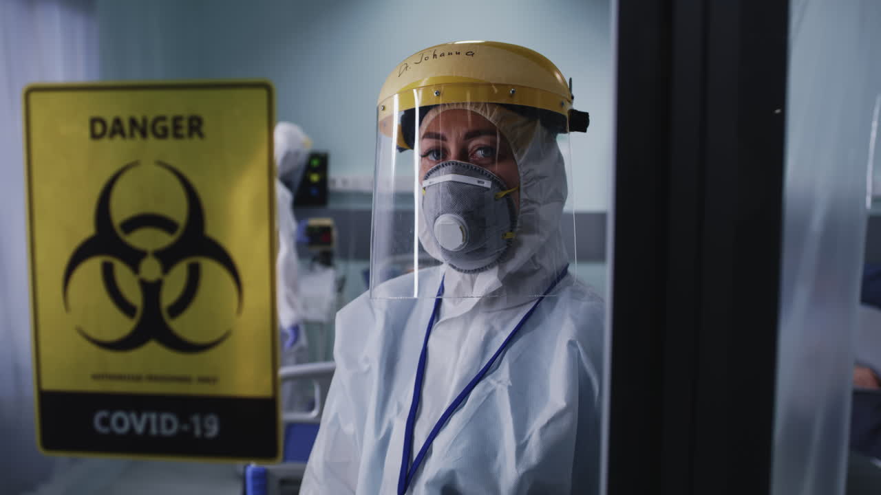 Healthcare worker in full PPE with COVID-19 biohazard sign in a hospital