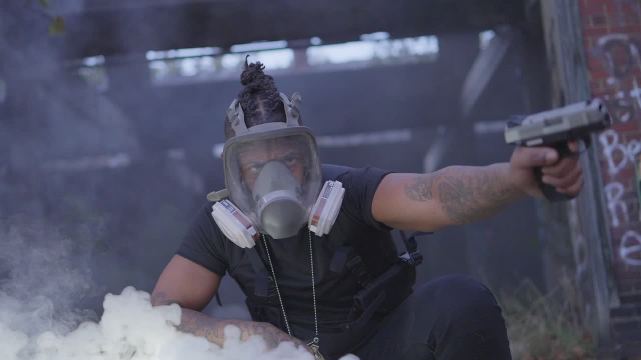 Cinematic shot of a masked man in tactical gear pointing a pistol amid smoke in a graffiti-covered abandoned structure