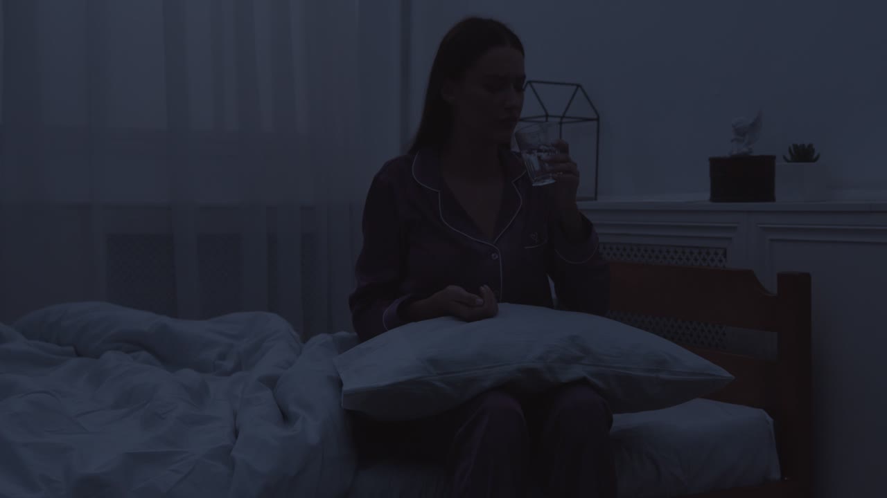 mujer bebiendo agua en la cama por la noche