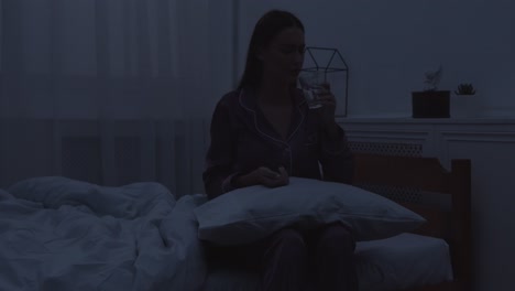 mujer bebiendo agua en la cama por la noche