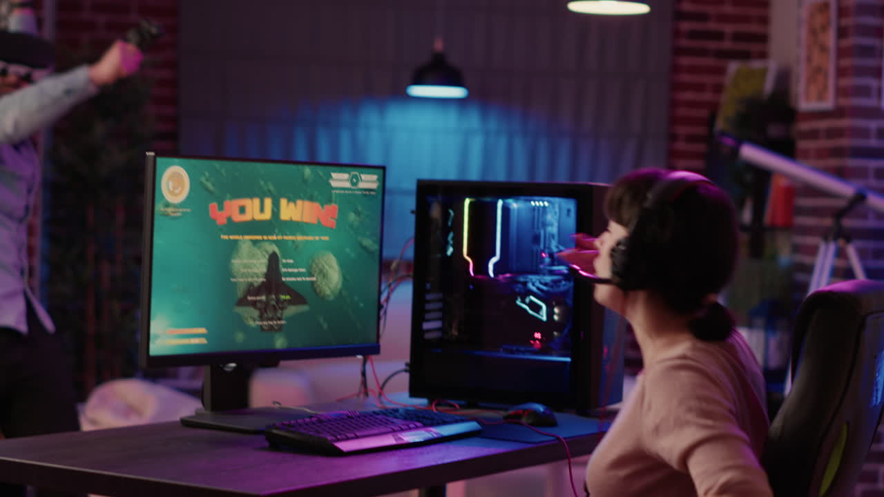 Handheld shot of gamer girl celebrating winning first place in action space game while man is playing first person shooter