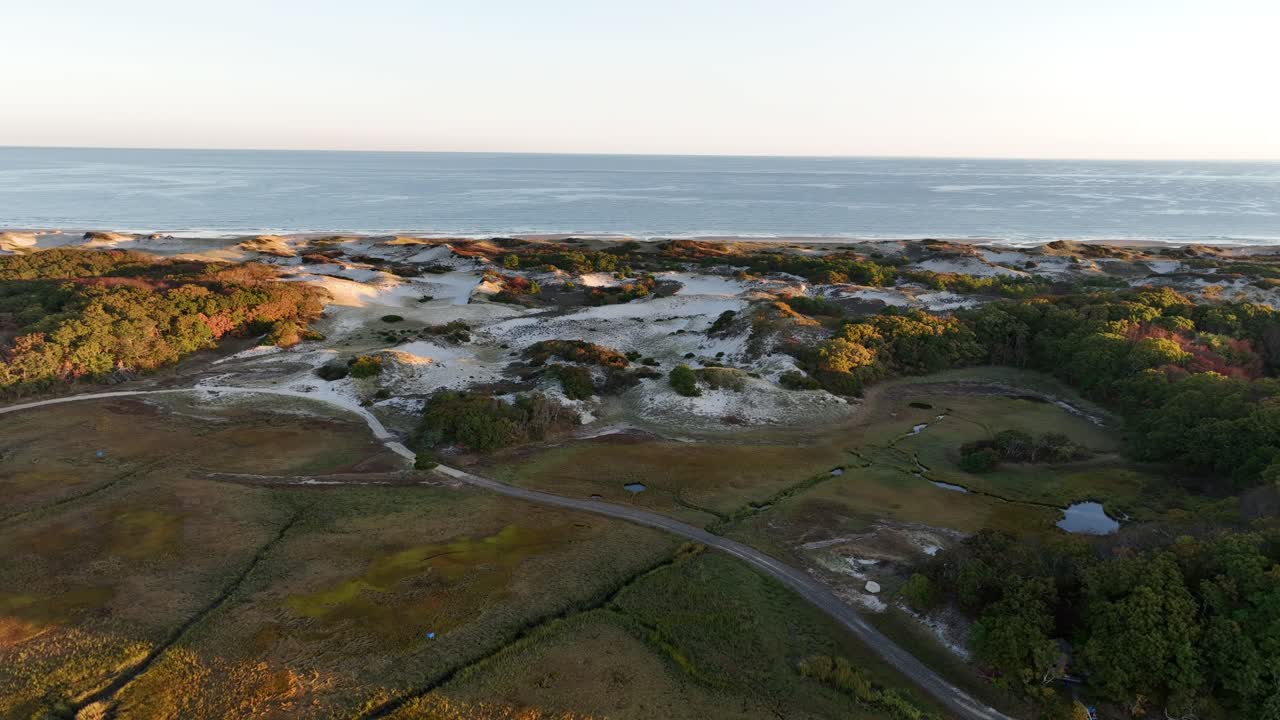 Cape cod's sand dunes and salt marsh at sunrise with ocean in the distance, aerial view