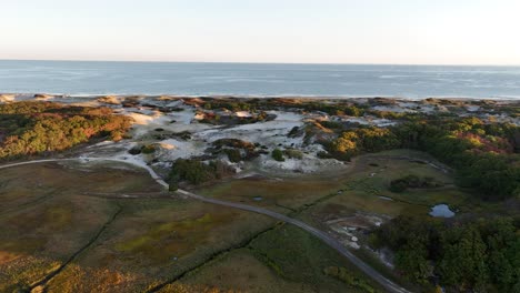 cape cod's sand dunes and salt marsh at sunrise with ocean in the distance, aerial view