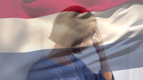 composición digital de la bandera de los países bajos ondeando contra una mujer caucásica estresada en el hospital
