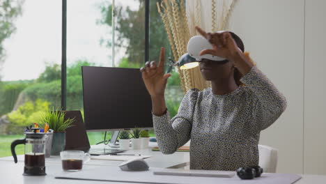 woman working from home office at desk wearing vr headset interacting with ar technology