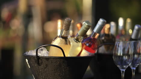 botellas de vino en un cubo de hielo, bebidas frías en un evento, boda, copas de vino, alcohol para la fiesta, pan disparado en cámara lenta, espacio de copia