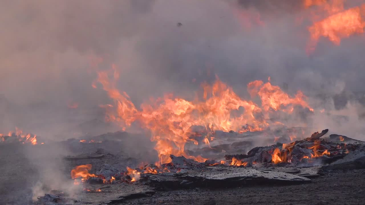 Pallet e scatole bruciano a terra mentre i vigili del fuoco combattono le strutture in fiamme durante il disastro dell'incendio Easy Fire sulle colline vicino a Simi Valley, California meridionale.