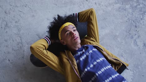 african american man wearing lying on his skateboard in empty parking garage