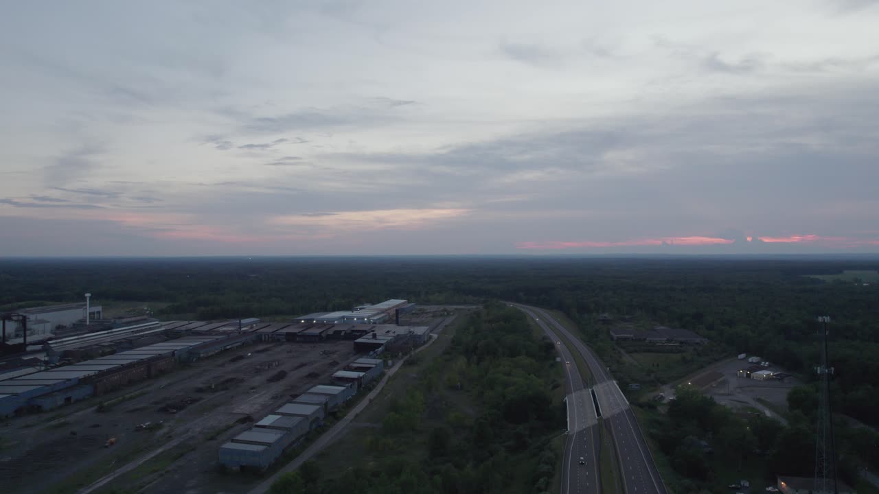 disparo en ángulo alto sobre filas de godowns junto a una carretera con un puente elevado durante la noche