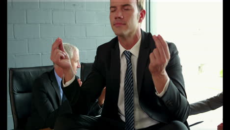 Man-doing-yoga-on-table-while-business-team-arguing