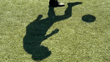 close up of a young soccer man training freestyle tricks with the ball on a street football pitch on a sunny day