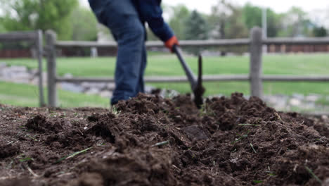 man digging using pick axe in a yard