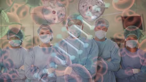 Animation-of-dna-strand-covid-19-cells-over-diverse-surgeons-wearing-face-masks-in-operating-theatre