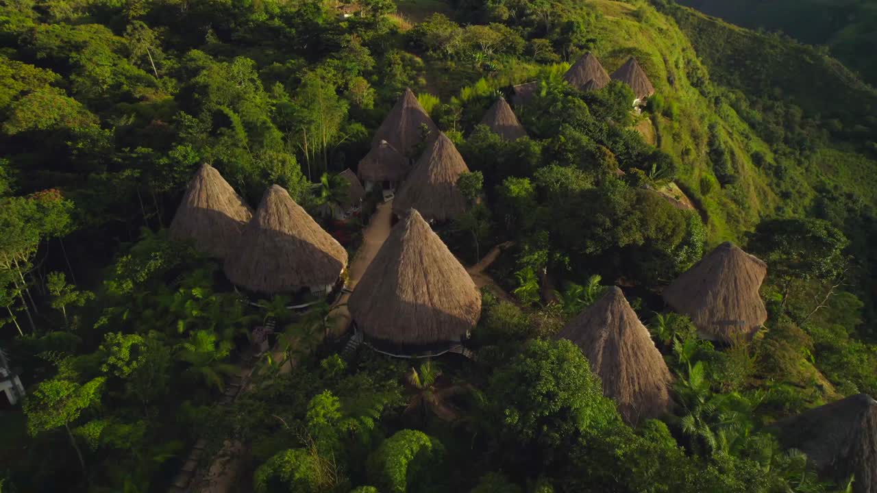 conjunto de cabañas indígenas sudamericanas con techo de paja rodeadas de selva al atardecer
