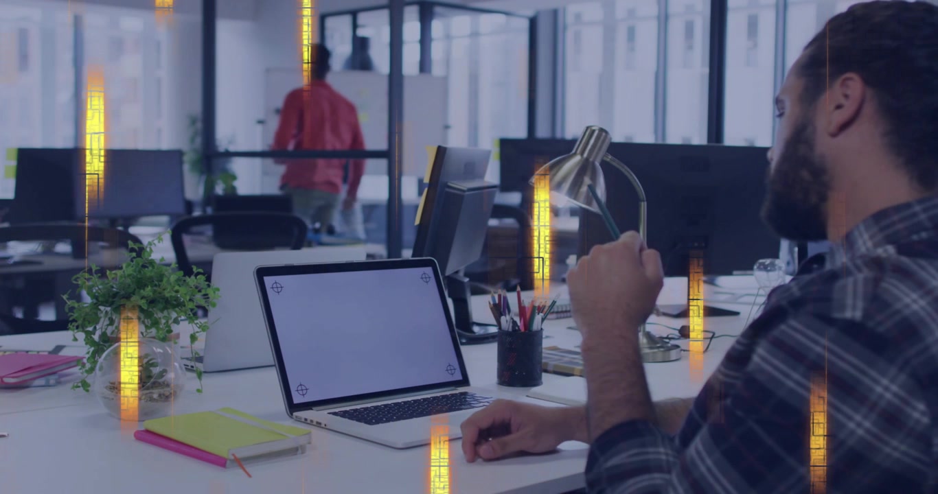 Bearded man adjusting lamp in office as peer passing glass, cutting laptop glare, golden overlay