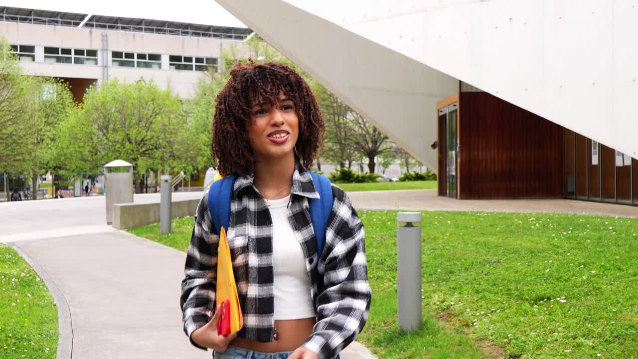 Ung kvinnelig student som går på universitetsområdet