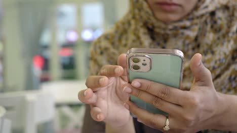 woman in hijab using phone in cafe