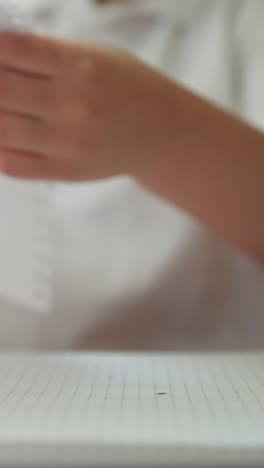 Little boy pulls to tear out notebook page with drawing at table closeup. Preschool student with handdrawn picture stands up from workplace in class