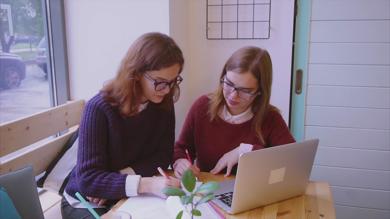 dos estudiantes estudiando en una cafetería